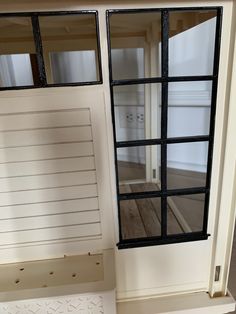 an open window on the side of a white door with shutters and wood flooring