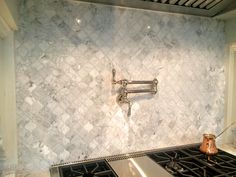 a stove top oven sitting inside of a kitchen next to a wall mounted faucet