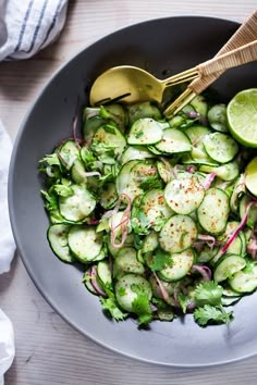 a bowl filled with cucumbers, onions and cilantro on top of a wooden table