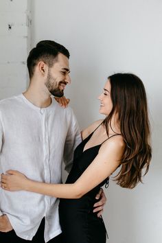 a man and woman standing next to each other with their arms around each other smiling