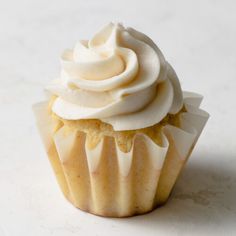 a cupcake with white frosting sitting on a table