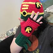 a woman wearing a red and green crocheted hat holding up her hand to the camera