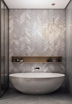 a large white bath tub sitting next to a wooden shelf in a bathroom with herringbone tiles on the walls