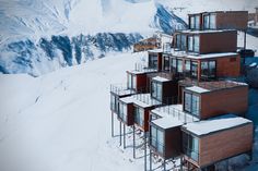 a group of houses in the snow with mountains in the background