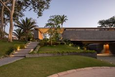 the house is surrounded by lush green grass and trees, with stairs leading up to it