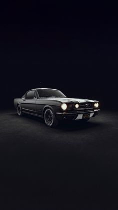 an old black car in the dark with lights on it's headlamps