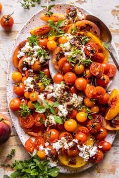 a platter filled with tomatoes, cheese and herbs