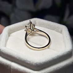 a gold ring sitting on top of a white cloth covered display case in a box