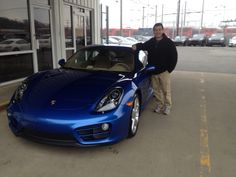 a man standing next to a blue sports car