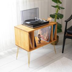 a record player sitting on top of a wooden table next to a potted plant