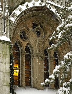 an old building with snow on the ground and trees in front of it that are covered in snow