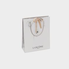 a white paper bag with a bow on the handle and lancomme logo in front