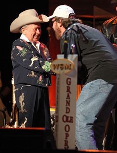 two men standing next to each other in front of a sign with the words grand opera written on it