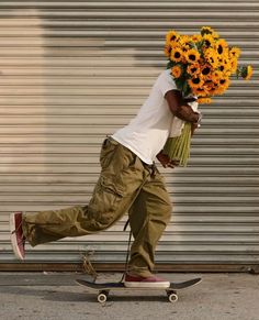 a man riding a skateboard down a street holding flowers on top of his head