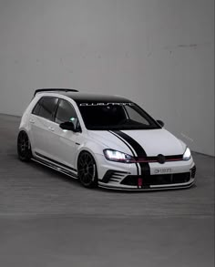 a white car with black stripes parked in a parking garage next to a wall and concrete floor