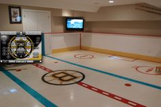 an ice rink with hockey equipment on the floor and two televisions in the background