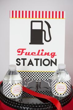 a fueling station sign and two soda cans on a tray with a red ribbon