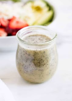 a glass jar filled with dressing next to a bowl of salad