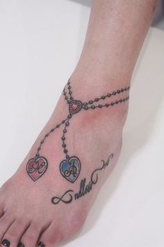 a woman's foot with two hearts and a cross tattoo on the top of it