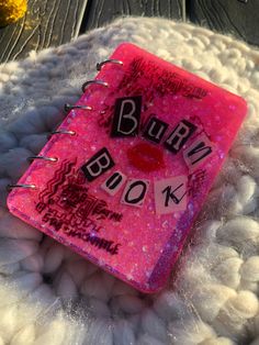 a pink book with the words burn on it sitting on top of some white balls