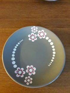 a plate with flowers painted on it sitting on a wooden table next to a cup and saucer