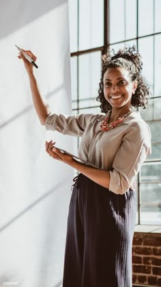 a woman standing in front of a whiteboard holding a pen and writing on it