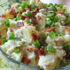 a glass bowl filled with potato salad on top of a green and white table cloth