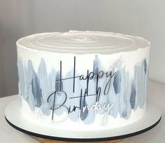 a birthday cake with blue and white paint splattered on it that says happy birthday