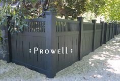 a black fence with the words prowell written on it in front of some trees