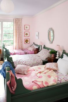 two beds in a room with pink walls and green headboards on the bed,