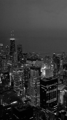 black and white photograph of city lights in the dark night sky from top of skyscrapers