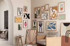 a living room filled with lots of art on the wall next to a table and chairs