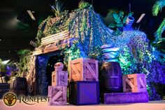 the entrance to an amusement park decorated with plants and barrels in front of a horse