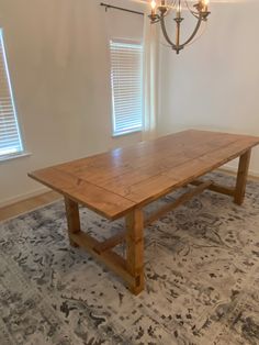 an empty room with a wooden table and chandelier hanging from it's ceiling