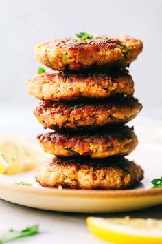 three crab cakes stacked on top of each other with lemon wedges in the background