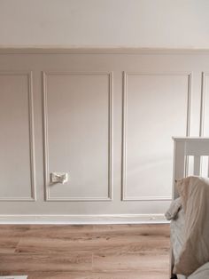 a baby crib in the corner of a room with white walls and wood floors