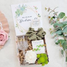 a gift box with flowers, cards and wine glasses