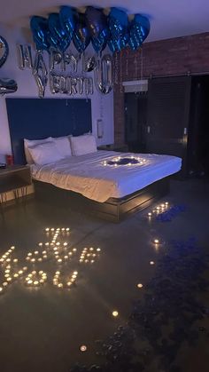 a bed that is in some kind of room with candles on the floor and balloons hanging from the ceiling