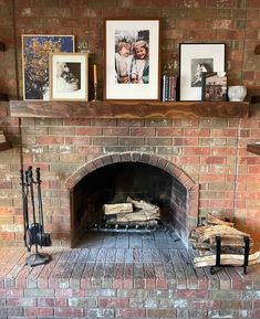 a brick fireplace with pictures on the mantle and firewood logs in front of it