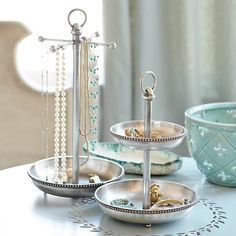 three tiered trays with jewelry on them sitting on a table next to a vase