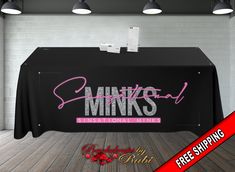 a black table with pink writing on it and some lights hanging from the ceiling above it