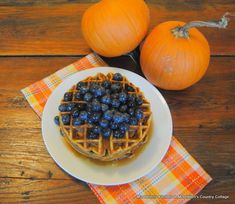 two pumpkins and some blueberries are sitting on a table next to a waffle