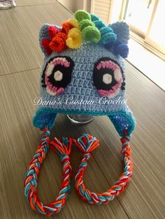 a crocheted pony hat with colorful braids on the bottom and ears is sitting on a table