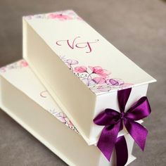 two white boxes with purple ribbons on them