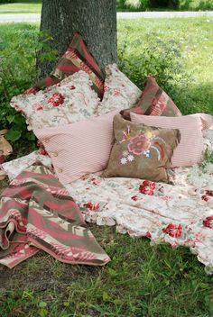 a pile of pillows sitting under a tree