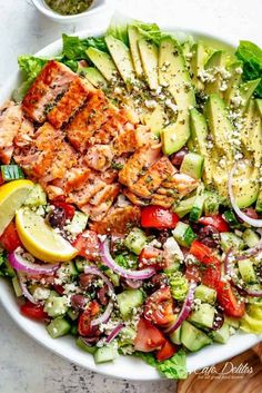 a salad with salmon, avocado, tomatoes and cucumber