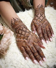 a woman's hands with hennap and flowers on top of white fur