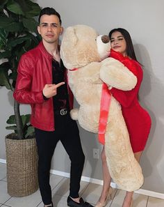 a man and woman posing with a giant teddy bear