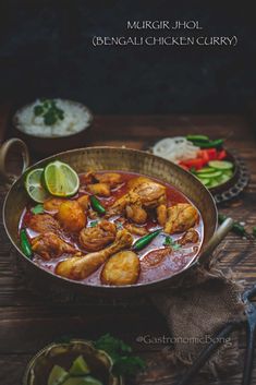 chicken curry is served in a bowl with limes and cilantro on the side