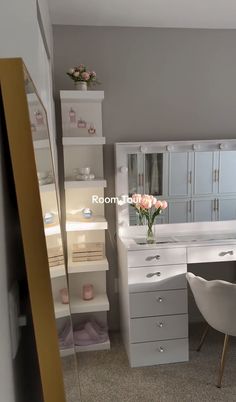 a white desk and chair in a small room with drawers, shelves, and shelving